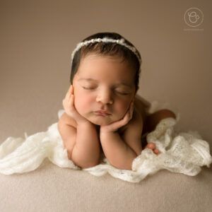 Photoshoot of Newborn baby sleeping whilst resting head in hands